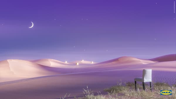A white and blue-striped BERGMUND chair, with black legs, stands on a grassy ridge above a violet-coloured desert landscape.