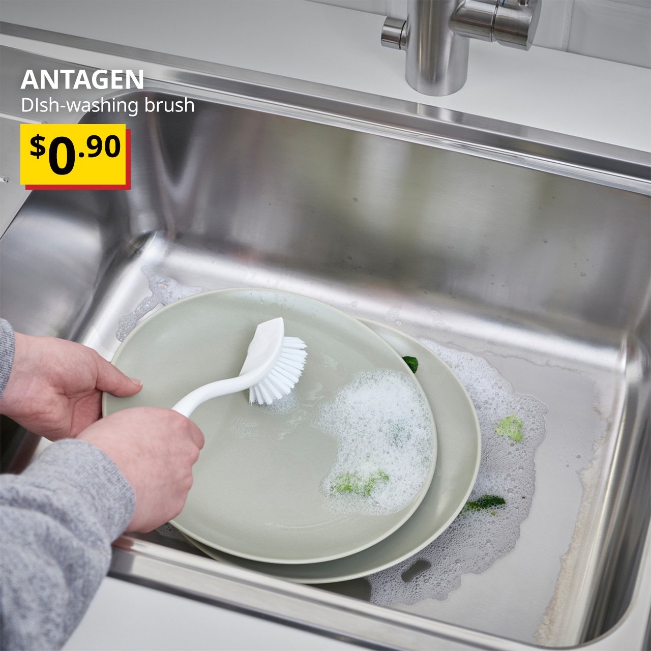 A white ANTAGEN dish-washing brush in kitchen setting. Black text on top left of the image reads: ANTAGEN, Dish-washing brush. Price: $0.90.