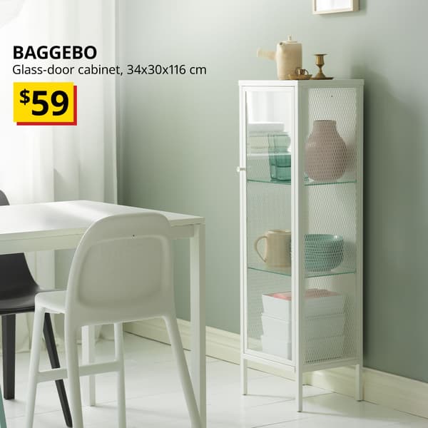 A white BAGGEBO glass-door cabinet is positioned beside a dining table with a vase, mugs, and deep plates displayed on the first two shelves, while white KUGGIS containers are stacked on the lower shelf. Text on the top left of the image reads: BAGGEBO, Glass-door cabinet, 34x30x116 cm, Price at $59.