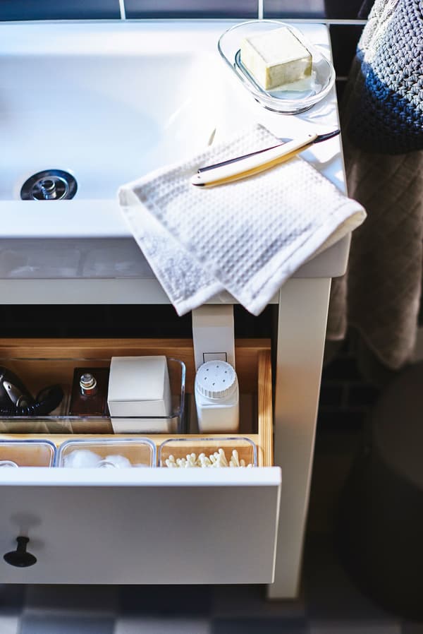 A white bathroom sink with drawer open below.