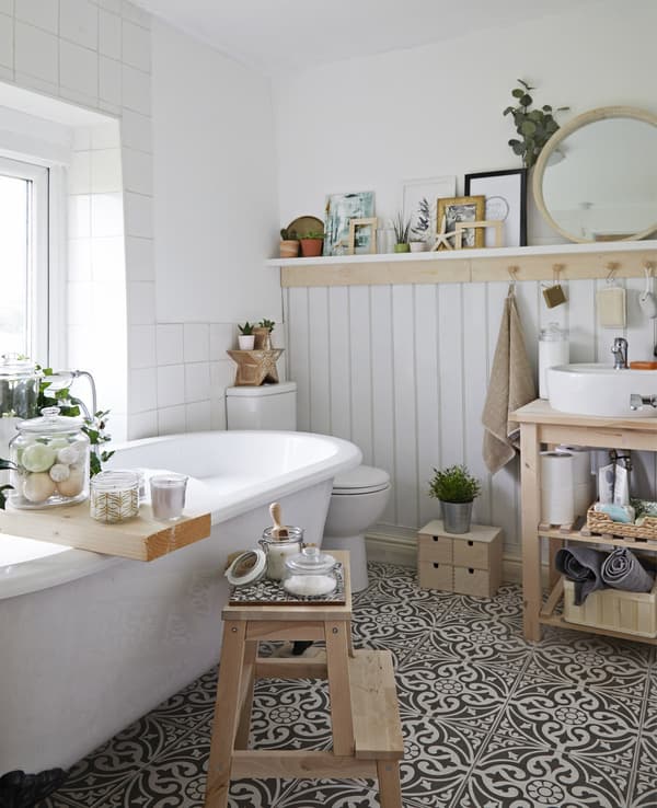 A white bathroom with wooden storage, glass jars and tiled floor.
