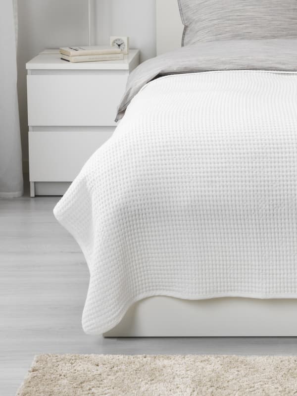 a white bedspread on top of a bed