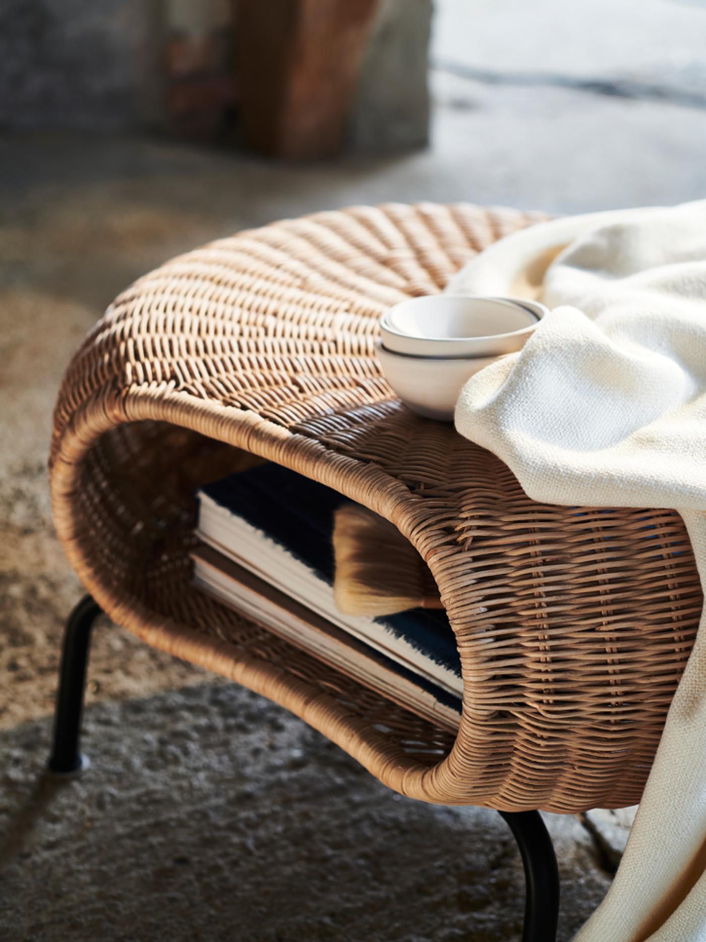 A white blanket and three white bowls on a GAMLEHULT footstool with books stored inside.