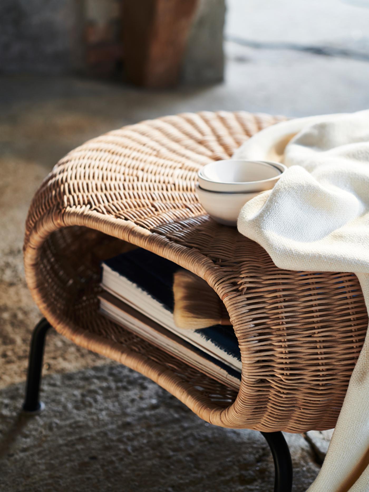 A white blanket and three white bowls on a GAMLEHULT footstool with books stored inside.