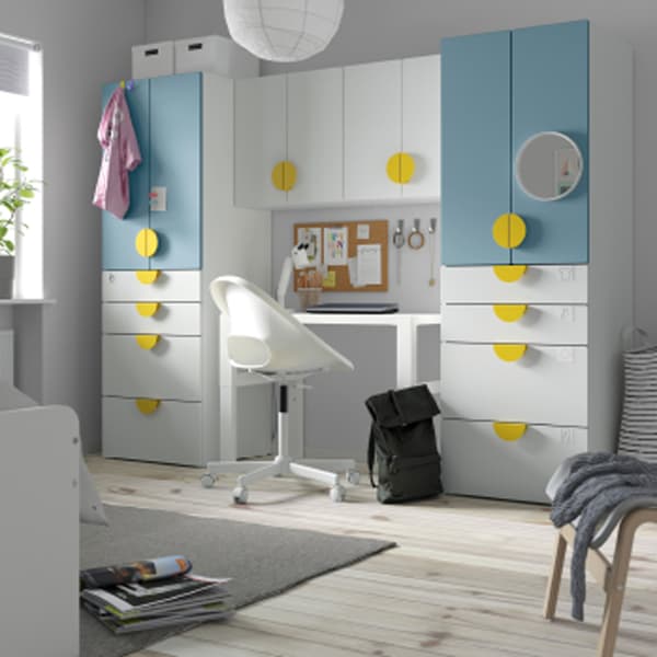 A white/blue SMÅSTAD/PLATSA storage combination stands against a wall in a child’s room with a wooden floor.