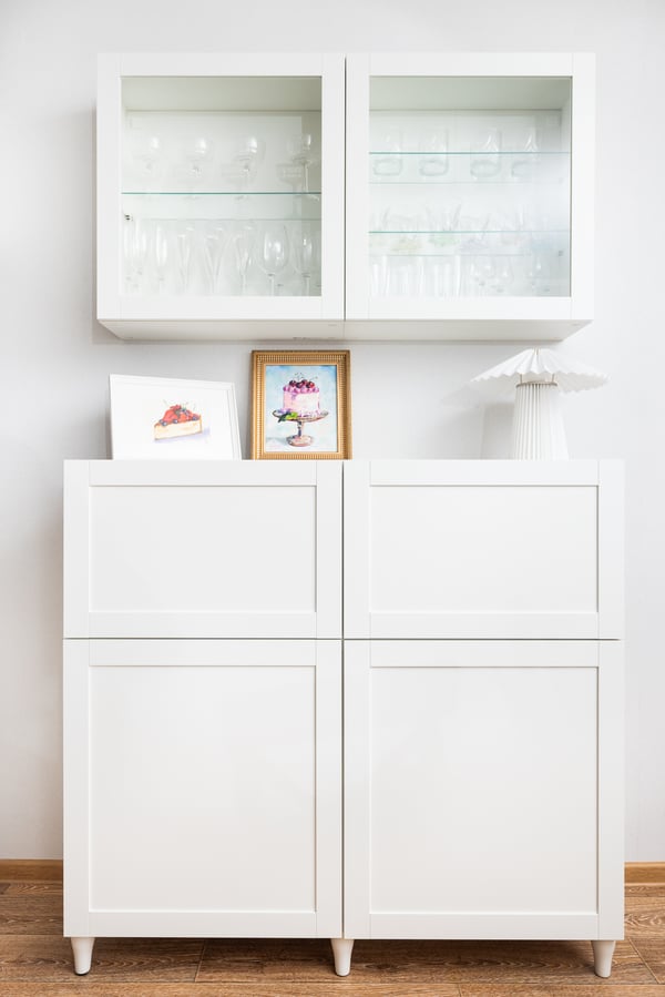A white cabinet with glass-front upper doors and decorative items on display. The unit adds an organised and minimalist touch to the dining area.