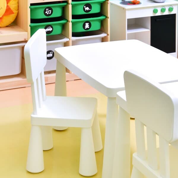 A white children chair and table is placed on a yellow floor.