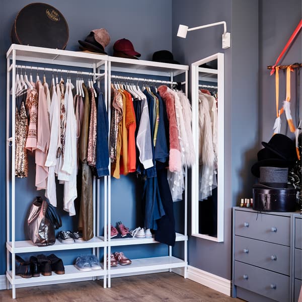 A white coat rack with shoe storage, a white mirror, a white wall lamp and a blue-grey chest of drawers.