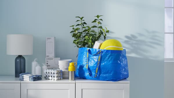 A white console with an IKEA Blue Bag and IKEA products sitting on the surface