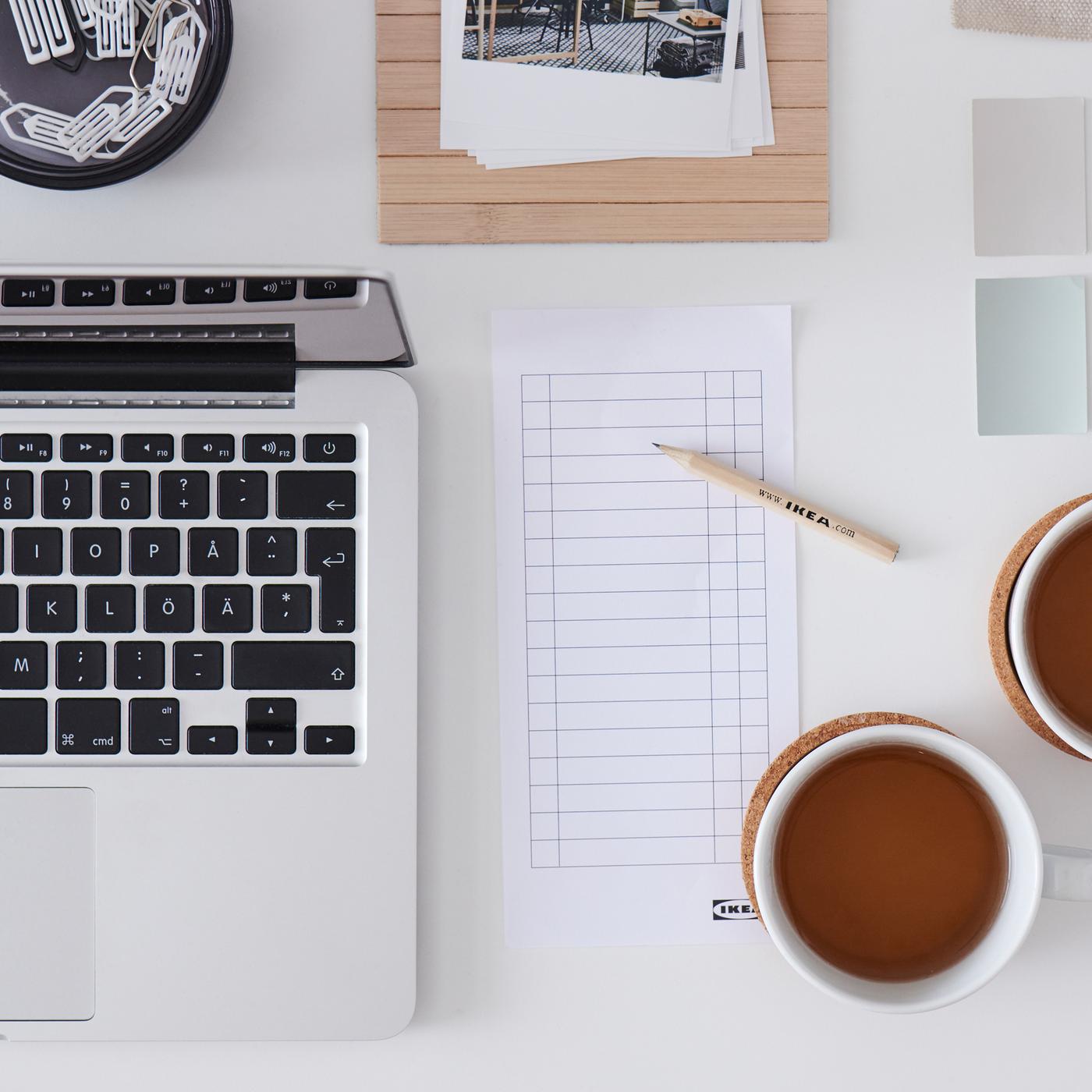 A white desk with a laptop, two cups of tea, a checklist, a wooden IKEA pencil, inspirational images and colour swatches.