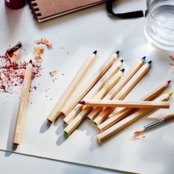 A white desktop with colourful pencils and pencil shavings.