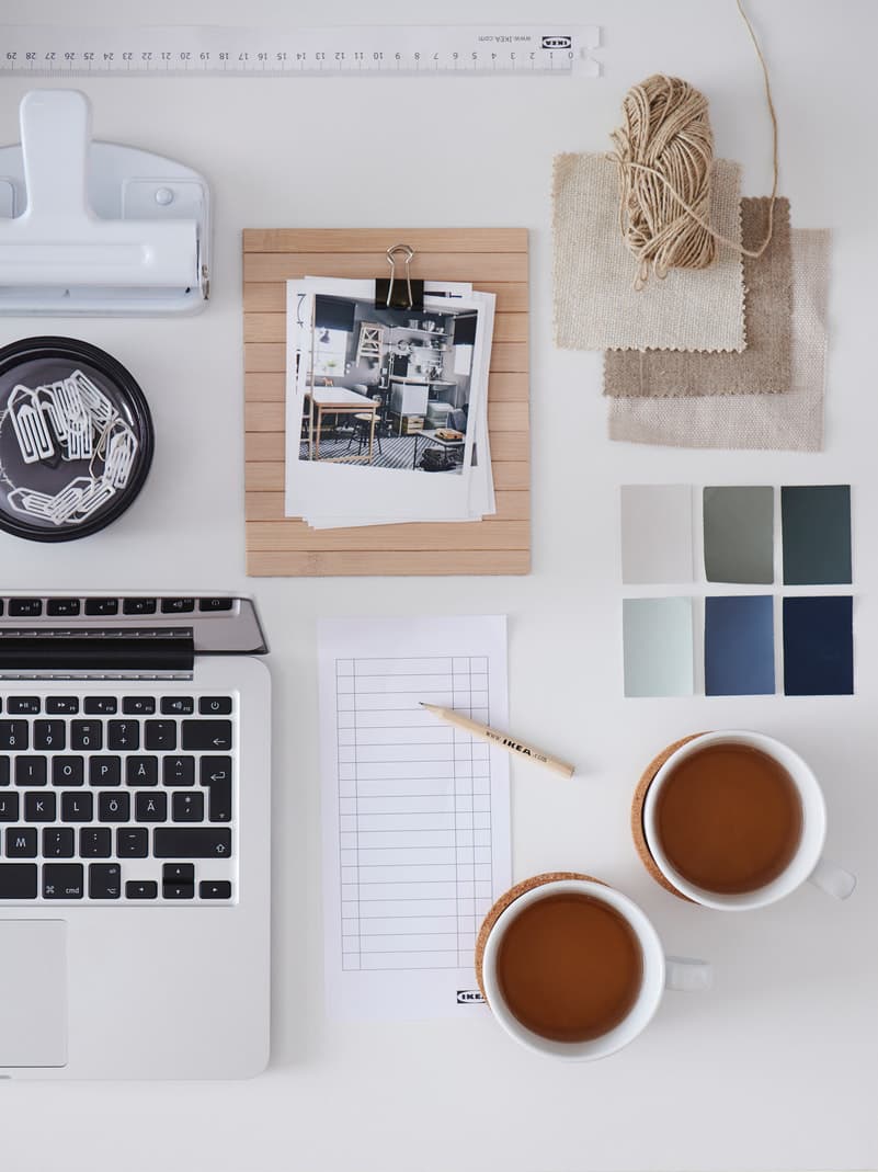 A white desktop with scattered but symmetrically arranged office accessories and desk-work paraphernalia.