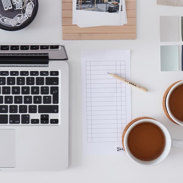 A white desktop with scattered but symmetrically arranged office accessories and desk-work paraphernalia.