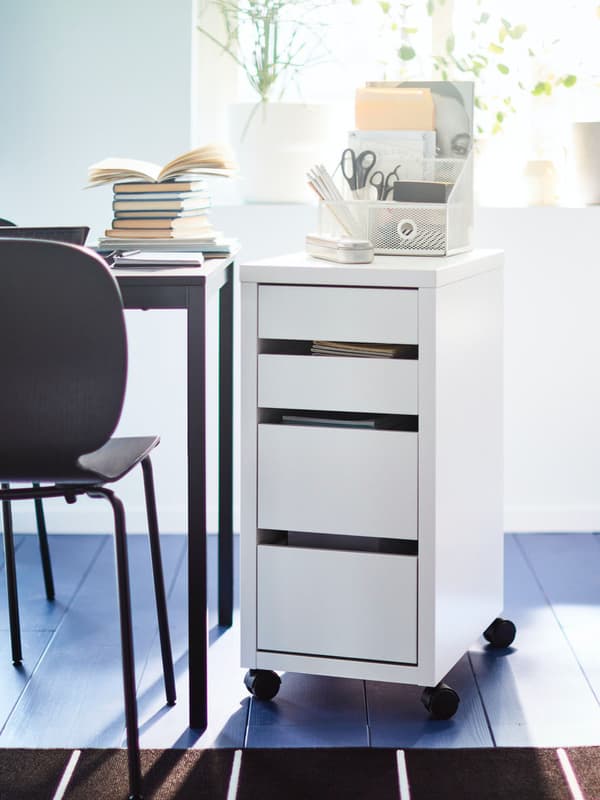 a white drawer unit beside a desk with chair