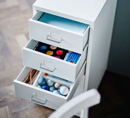 A white drawer unit on casters with three of the drawers open
