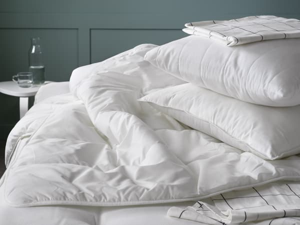 A white duvet inset sitting on a bed with white pillows on top.