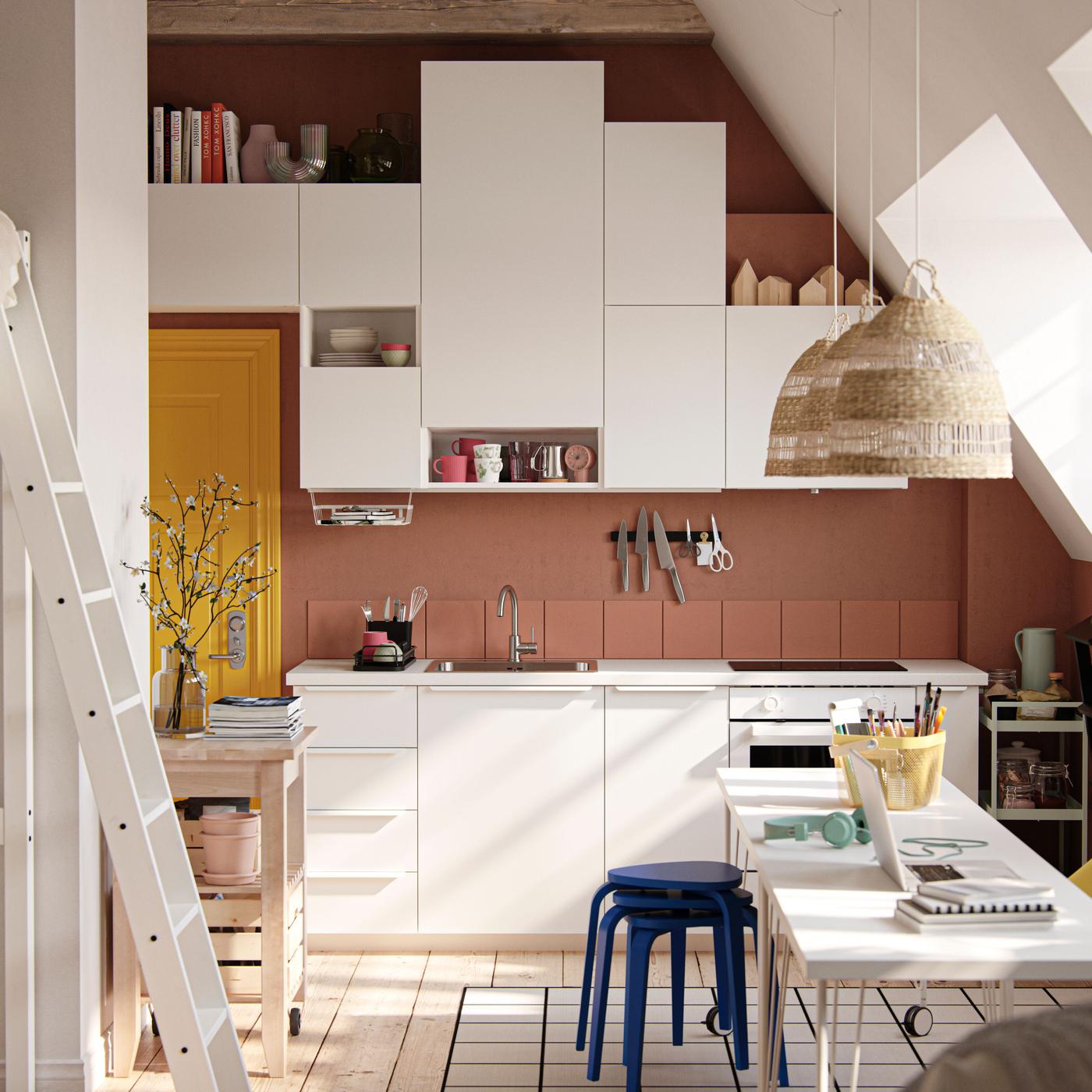 A white eclectic kitchen with a clay coloured wall.