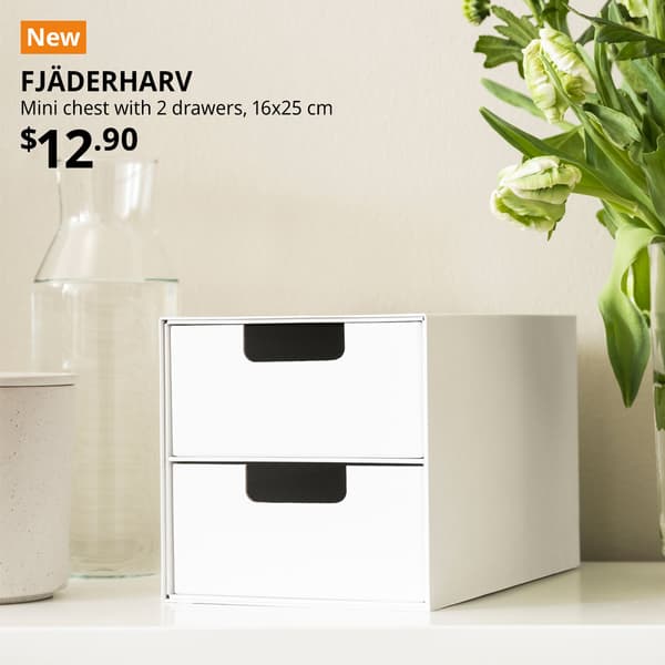 A white FJÄDERHARV mini chest with 2 drawers is placed on a white countertop. An orange "NEW" label is on the top left of the image with black text that reads: FJÄDERHARV, Mini chest with 2 drawers, 16x25 cm, Price is $12.90.