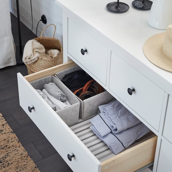 A white HEMNES chest of drawers is open, and KOMPLEMENT light gray boxes inside help organize clothes.