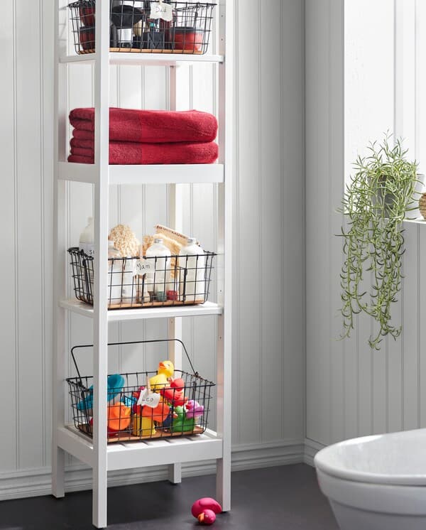 A white HEMNES shelf unit with black PLEJA wire baskets storing towels, bath toys, spa stuff and more on the four shelves.