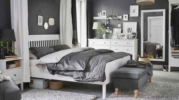 A white IDANÄS bed, bedside table and chest of drawers stand in a bedroom, with LUKTJASMIN bed linen on the bed.