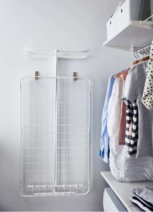 A white IKEA MULIG foldable drying rack attached to a wall near a laundry area.