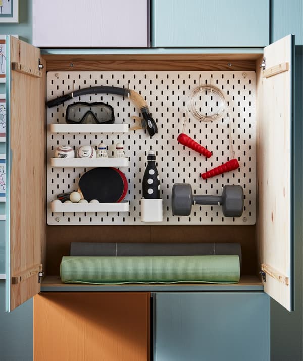 A white IKEA SKÅDIS pegboard combination shown inside an IVA storage unit with sports equipment attached.