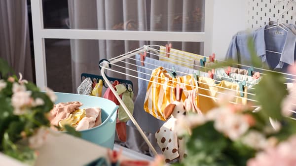 A white JÄLL drying rack with clothes held by clothes pegs and a hanger with 8 grip clips, plus a flexible laundry basket.