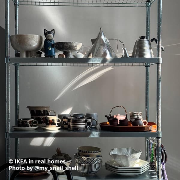 A white KALLAX shelving with inserts is placed next to the window in a living room setting with plants placed on top. IKEA in real homes Photo by @my_snail_shell