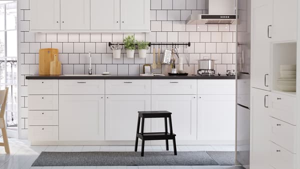 A white kitchen and white wall cabinets with SÄVEDAL framed white doors, white tiles, a gas hob, and a white floor.