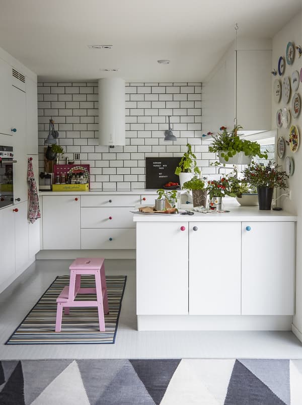 A white kitchen with colourful stepstool and rug.