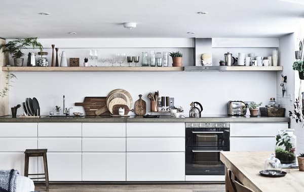 A white kitchen with concrete worktops and shelving.