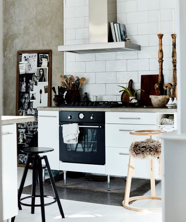 A white kitchen with extractor fan, white tiled walls and wooden accessories.