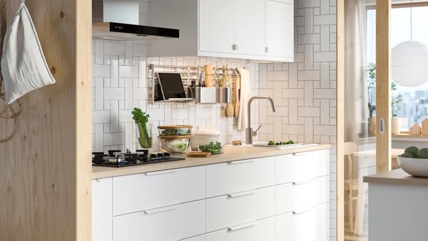 A white kitchen with KUNGSBACKA white drawers below a pale wood worktop and a white wall cabinet above.