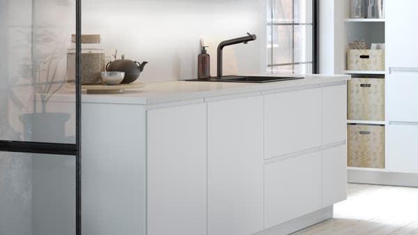A white kitchen with matt white kitchen doors and drawer fronts, a white worktop and a mixer tap.