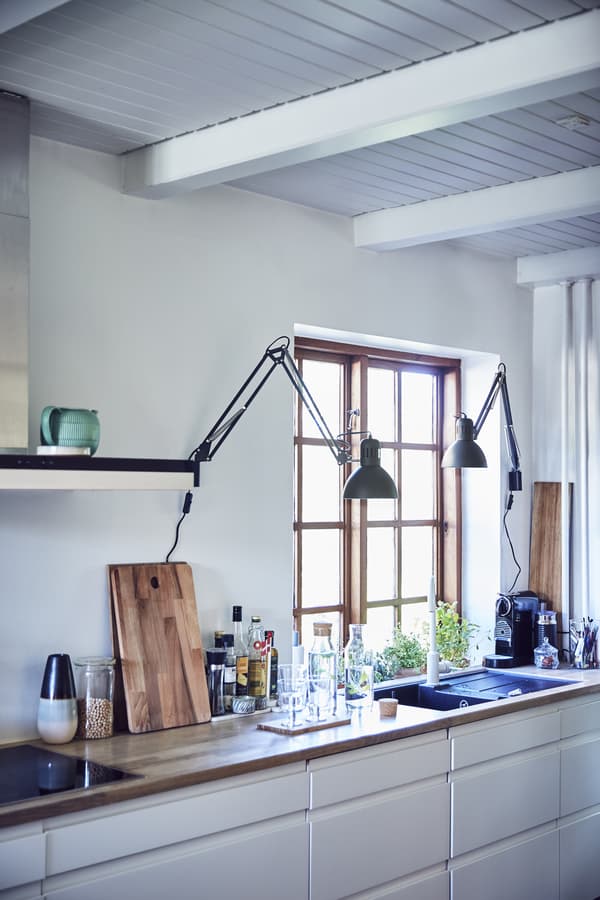 A white kitchen with two work lamps installed on the wall.