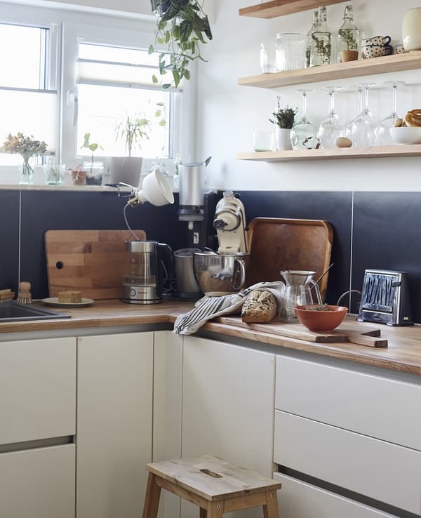 A white kitchen with wooden worktops and shelving.