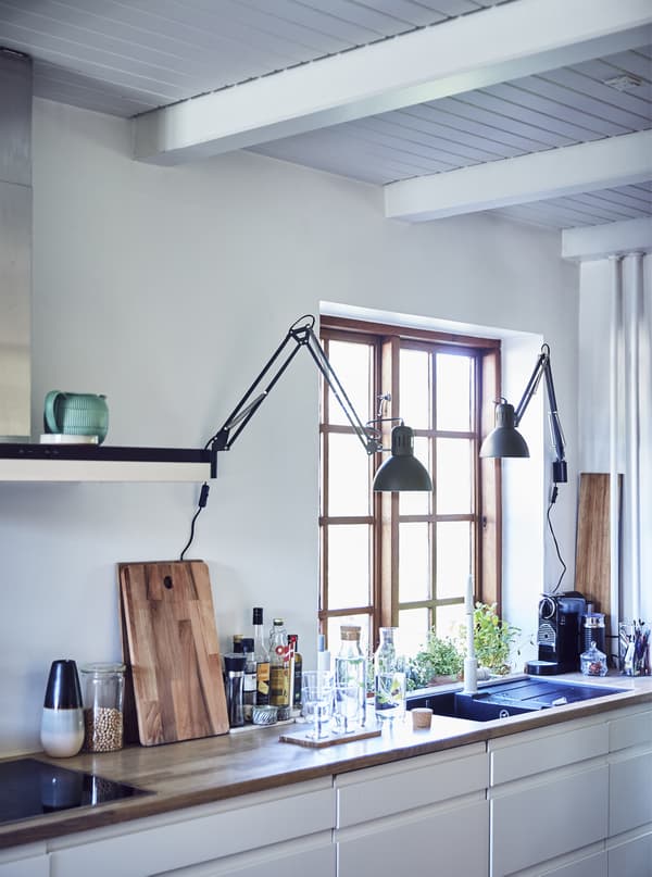 A white kitchen with worktops and lamps.