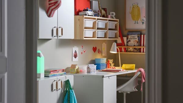 A white LÄRANDE desk with a pull-out storage unit, a white children’s desk chair and a pine/white wall storage combination.
