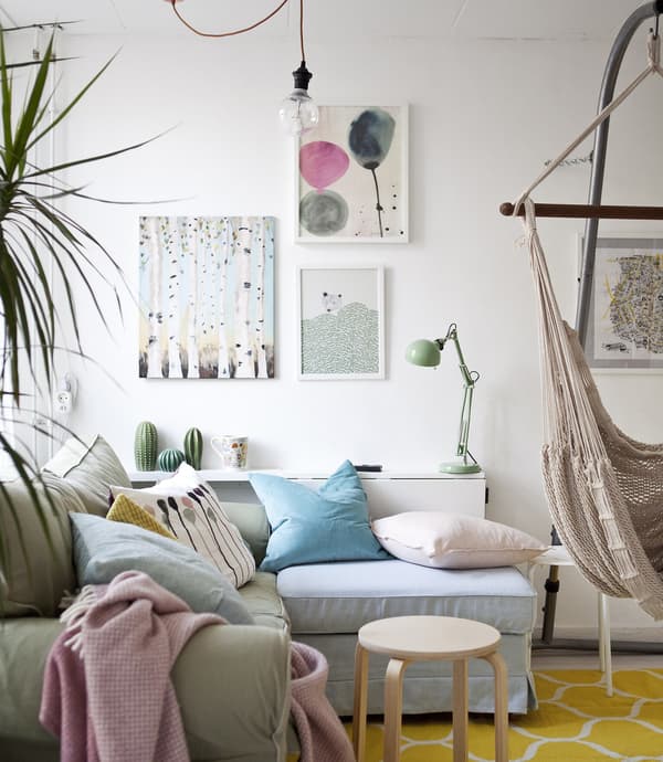 A white living room decorated with pastel accent colors, including a green sofa.