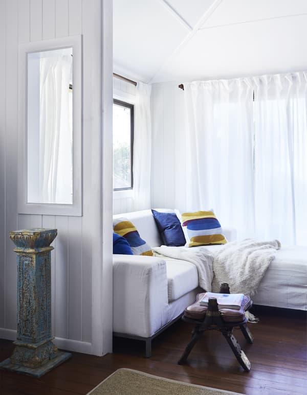 A white living room with brightly coloured cushions.
