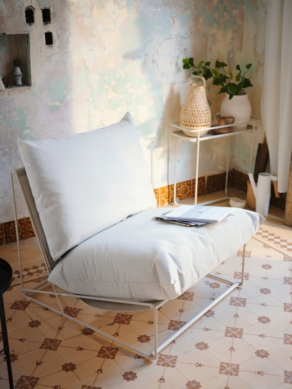 A white lounge chair standing on a patterned tile surface.