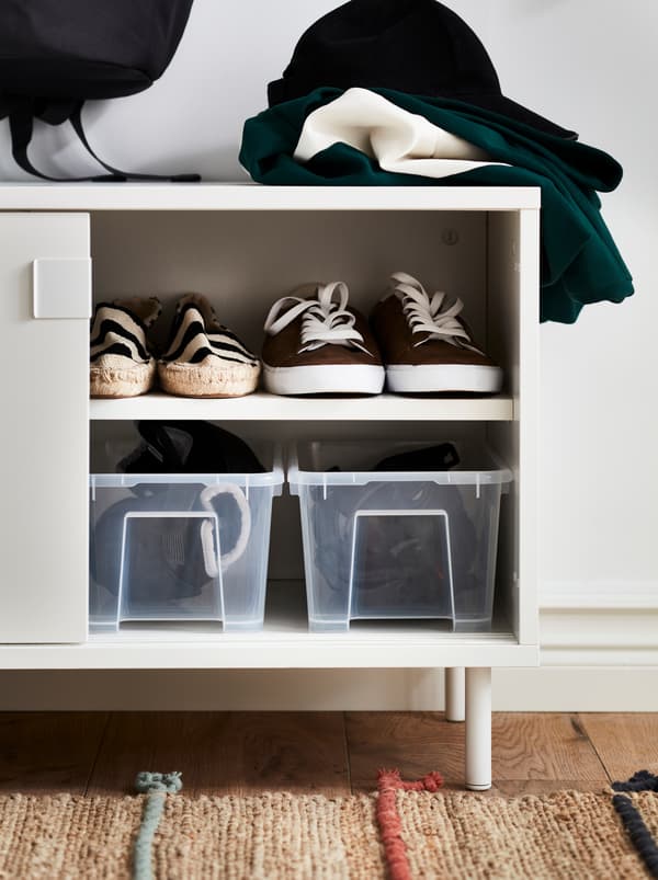 A white MACKAPÄR bench with storage compartments, opened to reveal clear boxes and shoes.