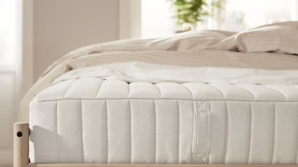 A white mattress with a beige bedding on it.