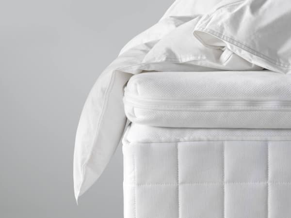 A white mattress with a white mattress topper on it.