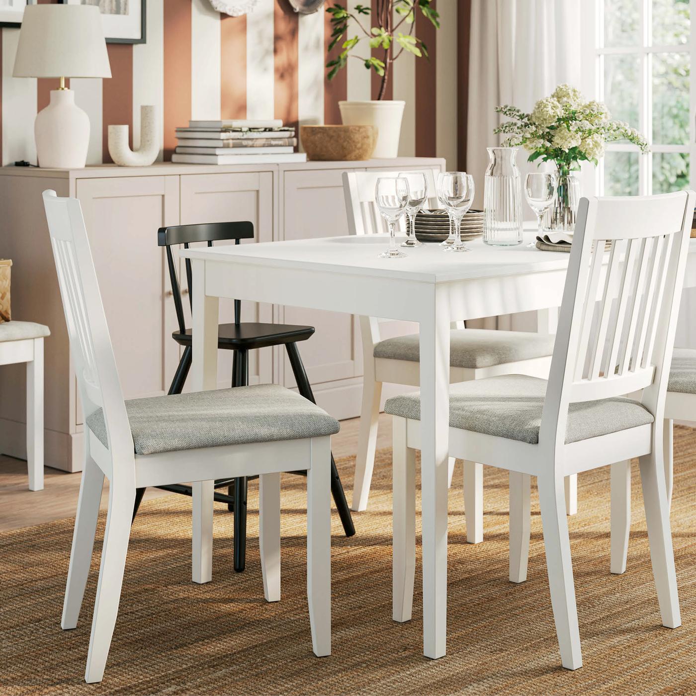 A white NÄSINGE chair with light beige cushion, set beside a dining table in a bright, airy room.