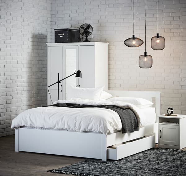 A white, Nordic-style bedroom with exposed brick walls painted white