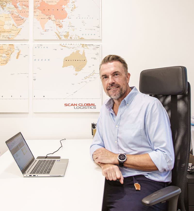 A white office space featuring a white desk with a laptop and a person sitting on a black office chair.