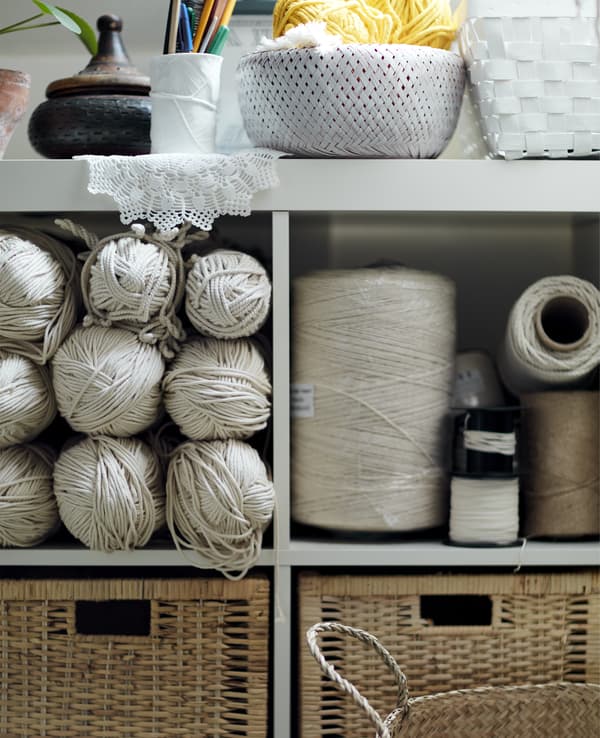 A white open shelving unit filled with craft supplies.
