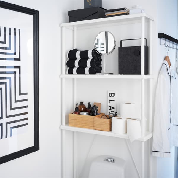 A white open storage that's placed above the toilet and transforms an often unused wall space into storage space.